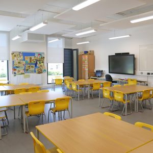JM2DYG Interior of a classroom in a newly built primary school in eastern London, UK. Shows desks, chairs and large TV monitor screen.Empty, no pupils.